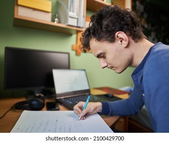 Software developer student working from home with laptop, computer, cellphone and notebook for his pHd