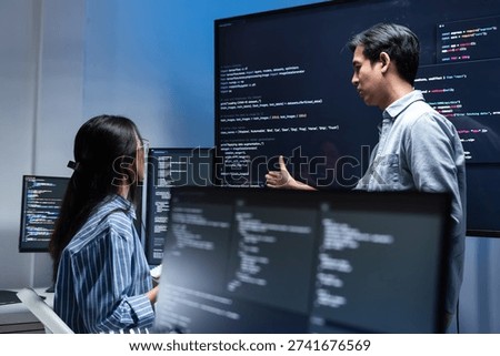 Software Developer Team working late in office at night. Programmer team collaboration, working on coding task, reviewing code while Male Programmer presenting code in the screen in tech office.