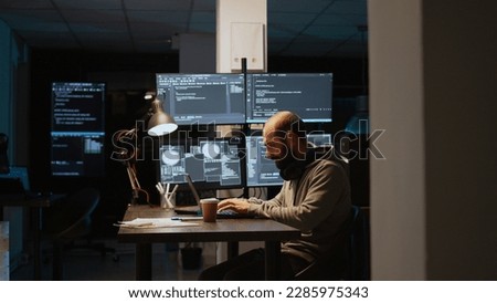 Software developer typing source code on laptop and multiple monitors, using programming language to create firewall security server. Male coder developing database cloud computing.