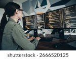 A software developer working diligently on her dual monitor setup, showcasing code and a focused environment in a modern workspace.