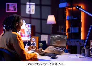 Software developer writes code on laptop screen while in apartment office using Java programming languages. Programmer remotely working on fixing database errors while working from home