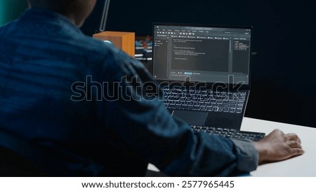 Software developer writes code on laptop screen while in apartment office using Java programming languages. Programmer remotely working on fixing database errors while working from home, camera A