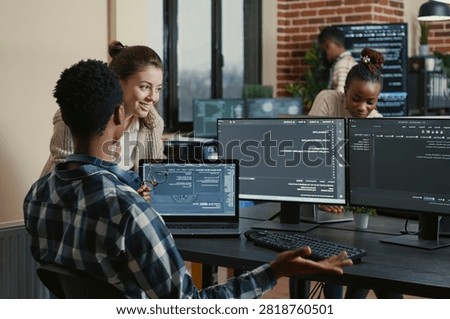 Software developers celebrate a successful code compile with a high five at an office desk, surrounded by screens showing programming and algorithms.