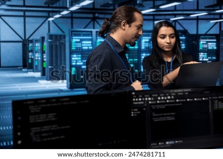 Software developers in data center running system diagnostic tests on laptop to fix problems. IT staff members deploying and error checking utilities on notebook to fix network issues performance