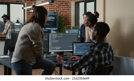 Software developers discussing about cloud programming innovation while the rest of the team joins the discussion. Programmers doing teamwork computing big data in server room.