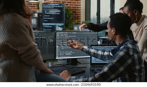 Software developers discussing about source\
code compiling discovers errors and asks the rest of the team for\
explanations in front of multiple screens running algorithms.\
Programmers doing\
teamwork.