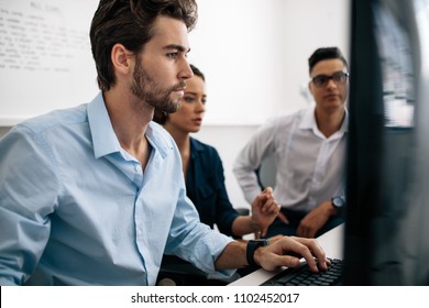 Software Developers Sitting In Front Of Computer And Working In Office. Two Men And A Woman Looking At Computer And Developing Applications In Office.