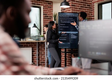 Software Developers Standing Near Vertical Screen Talking About Interface Bug And Slow Rate Of Processing Data. Cybernetics Engineers Reviewing Lines Of Code In Order To Secure Mainframe Database.