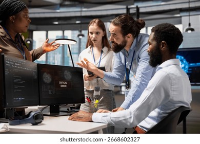Software developers working together, resolving critical error alert on screen in tech startup office, troubleshooting system warnings. IT workers using PC to repair office equipment bugs