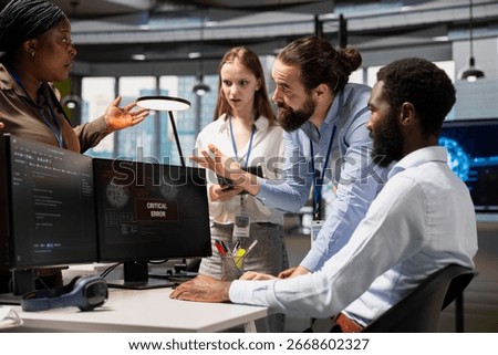 Software developers working together, resolving critical error alert on screen in tech startup office, troubleshooting system warnings. IT workers using PC to repair office equipment bugs