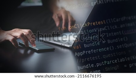 Software development, developing programmer coding javascript on laptop computer and using mobile phone for mobile apps design in software company office, digital technology concept