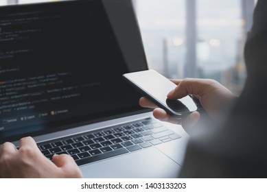 Software development, digital technology concept. Coding programmer, software developer developing mobile application on smart phone, programming Javascript on laptop with computer code on touchscreen