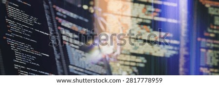 Software development panoramic background. Complex programming script on dark monitors with colorful syntax and bokeh effect.