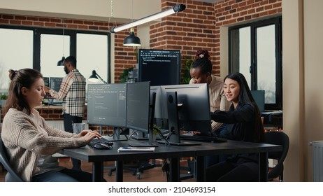 Software engineer typing source code on computer keyboard while colleagues sit down at desk for group project. App developer working in it startup company doing online cloud computing.