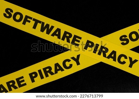 Software piracy alert, caution and warning concept. Yellow barricade tape with word in dark black background.