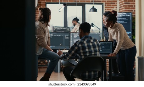 Software programmers discussing about online cloud computing while the rest of the team joins in front of multiple screens compiling code. Coders doing teamwork looking at running algorithms.