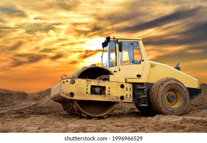 Soil Compactor for leveling ground for the foundation and on road construction. Road compaction equipment at construction site. Vibration single-cylinder road roller on amazing sunset background.