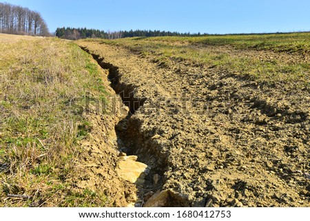 Soil erosion erosive groove in field road, damaged earth in farmer land.