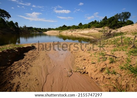 The soil on the shores of lakes or rivers is shallow because of the erosion of currents. causing nearby soil to flow into a lake or river There was a problem of shallow rivers, water shortages, and dr