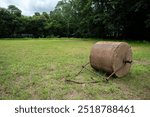 Soil roller laying of the field. Old rusty metal lawn roller on sports ground