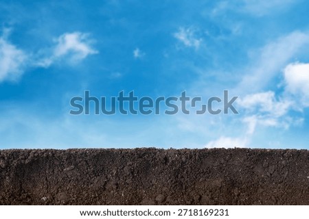 Soil under blue sky with clouds, closeup view