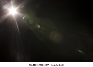 Solar camera lens flare light create hexagon of objective iris shapes of different colors depending on used antireflection coating of each lens surface on dark black background