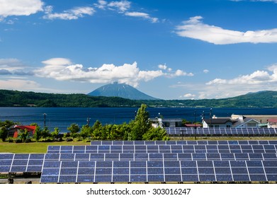 Solar cell panel and village in rural area with mountain landscape background