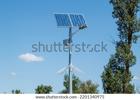 Solar device with street lamp on background of blue sky. Street light powered by solar panel with battery included. Alternative energy from the sun.