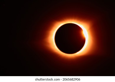 Solar eclipse with solar flare that makes for an orange glow around the black moon