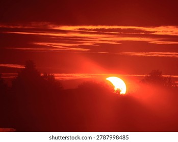 Solar eclipse occurring at either sunrise or sunset, with the moon partially obscuring the sun