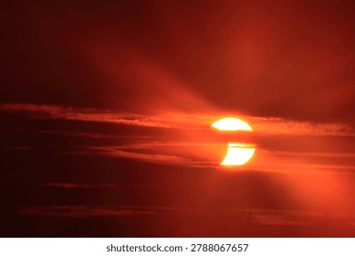 Solar eclipse occurring at either sunrise or sunset, with the moon partially obscuring the sun