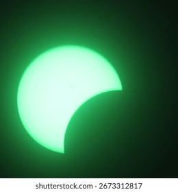 Solar eclipse seen through green welding glass.