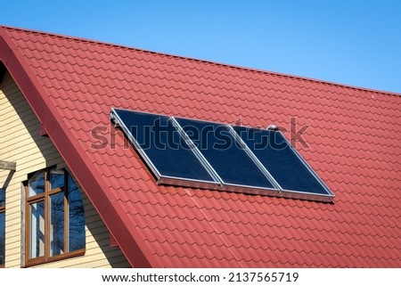 Solar energy. Water solar collector on a red metal roof.