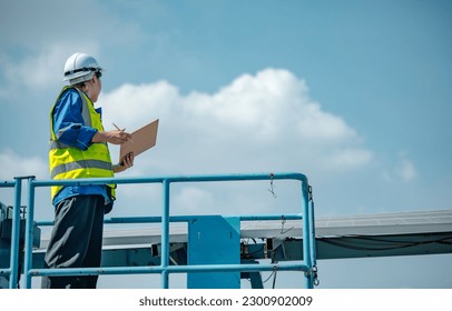 Solar engineers visually examine panel arrays on farm sites using blueprints and drawings to ensure that the alignment, surface, sunlight access, and structural stability meet standard requirements.