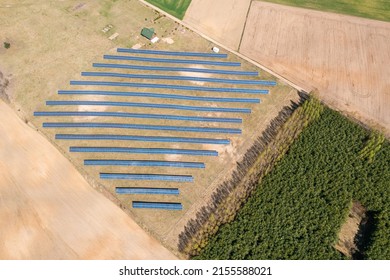 Solar Farm Aerial View, Rows Of PV Panels By A Small House
