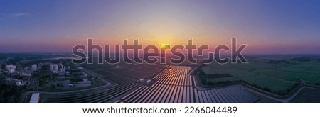 Solar Farm (solar cell) at sunset sky background with electric power generation in agricultural area . Renewable green alternative energy. Power plant. Solar photovoltaic rows array ground mounting.