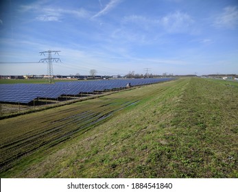 Solar farm and electricity poles servicing a nearby neighbourhood with nZEB buildings (near-zero energy buildings) alongside highway A50 APELDOORN, THE NETHERLANDS - APRIL 2018