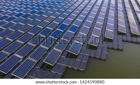 Solar farm panels in aerial view, rows array of polycrystalline silicon solar cells or photovoltaics in solar power plant floating on the water in lake, Alternative renewable energy.