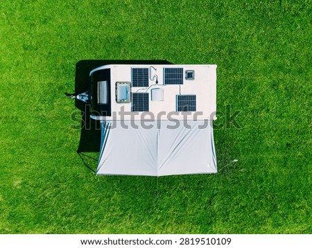 Solar panel array mounted on RV roof with awning set up on a vibrant green grassy field