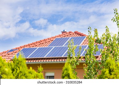 Solar panel cells on the roof of a new house against blue sky.