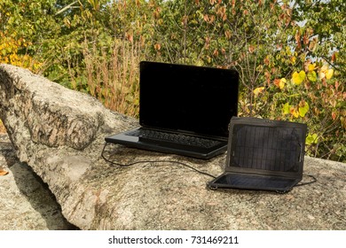 A solar panel charging a laptop at a remote work location