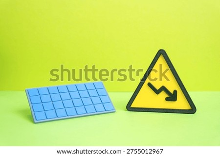 Solar panel and a downward arrow. Falling prices for solar technology and renewable energy equipment. Lower production costs but also reduced generation due to weather conditions or technical failures