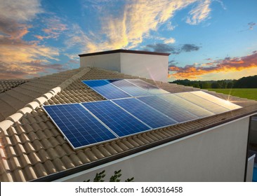 Solar Panel On A House Roof Reflecting The Sun And A Cloudy Afternoon Sky In Background