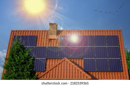Solar panel on red roof reflecting sun and cloudless blue sky. Roof with solar panel reflecting sun, in background perfect sky