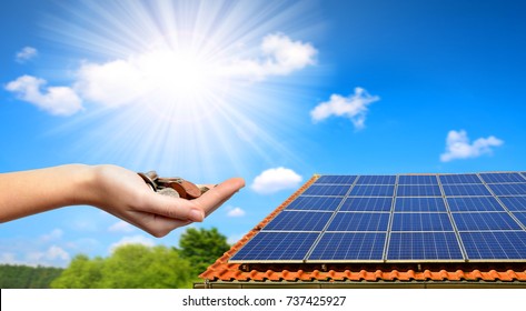 Sonnenkollektoren auf dem Dach des Hauses und Münzen in der Hand. Das Konzept der Geldeinsparung und der sauberen Energie.