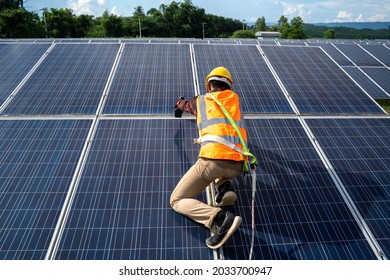 Solar Panel Technician With Drill Installing Solar Panels On Roof At Solar Panel Field,Environmental Protection,Alternative Clean Green Energy Concept. 