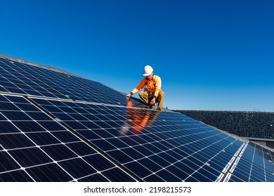 Solar panel technician with drill installing solar panels on house roof on a sunny day. - Shutterstock ID 2198215573