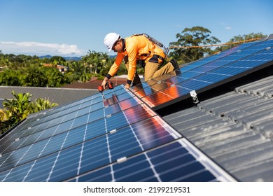 Solar panel technician with drill installing solar panels on house roof on a sunny day. - Shutterstock ID 2199219531