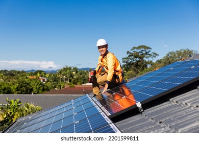 Solar panel technician with drill installing solar panels on house roof on a sunny day. - Shutterstock ID 2201599811