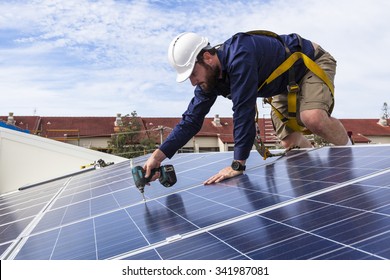 Solar panel technician with drill installing solar panels on roof - Shutterstock ID 341987081